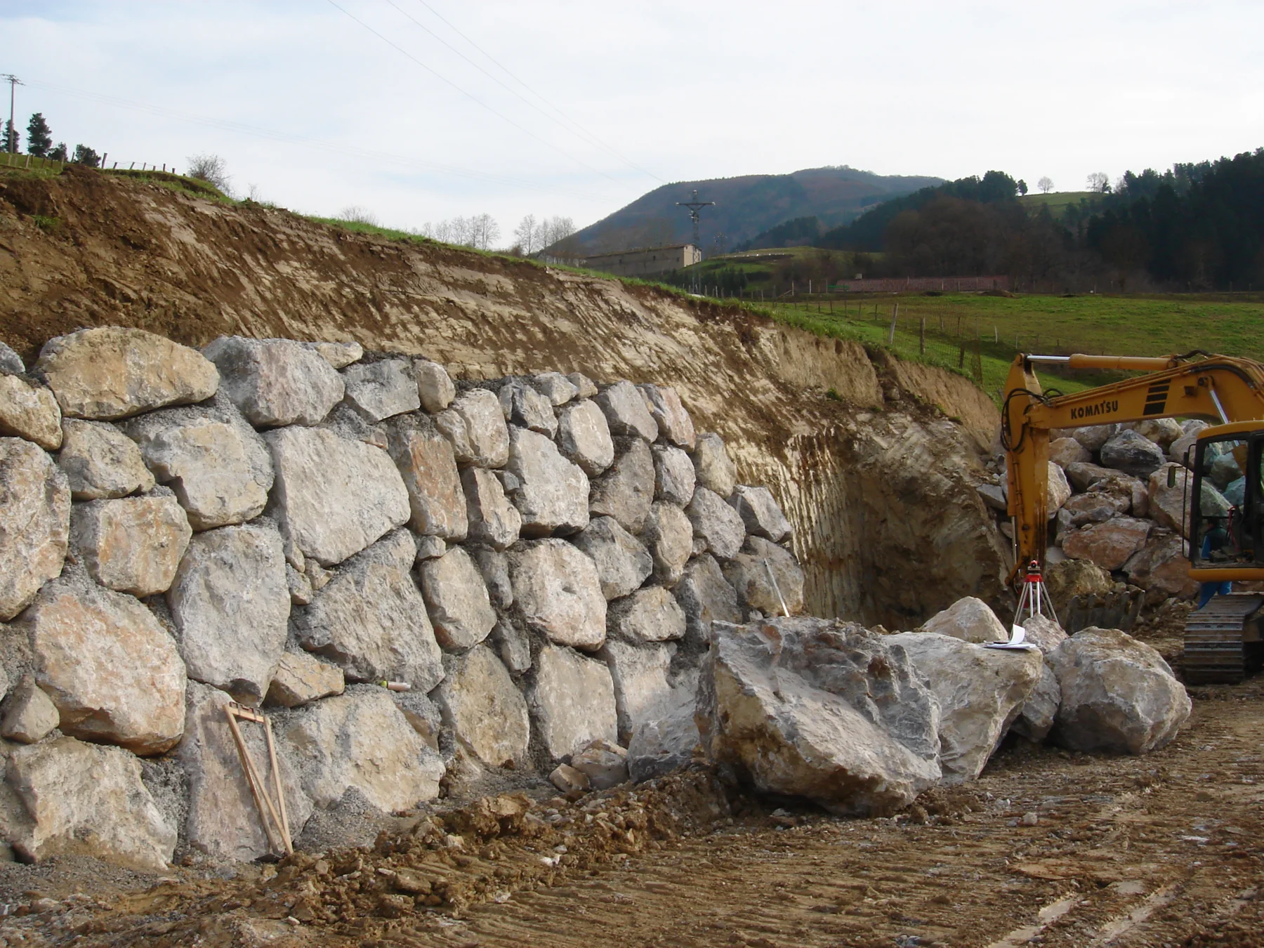 Large fitted natural boulder retaining wall under construction on a sloping site